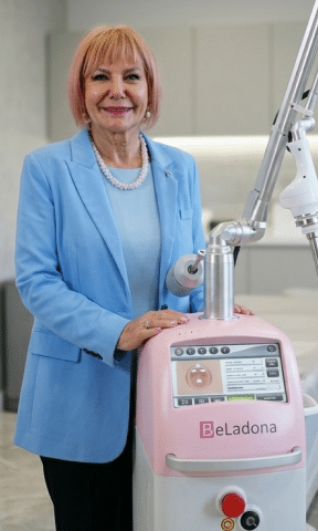 W klinicznym otoczeniu stoi kobieta w jasnoniebieskiej marynarce obok różowo-białego urządzenia medycznego marki BeLadona.